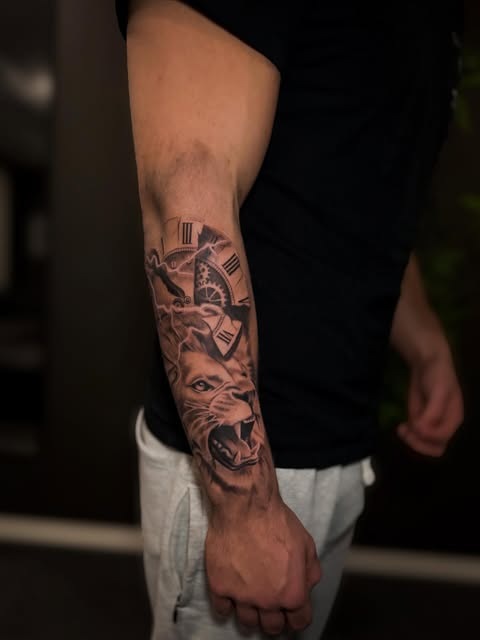 Løve og klokke på underarmen — tatovering av Daniel Borgeraas
